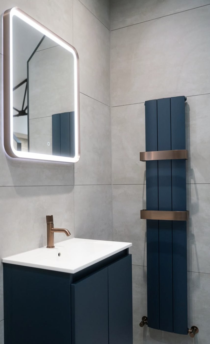 Navy vertical designer radiator with copper brackets in a bathroom